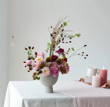 Colourful floral arrangements in a modern vase on table.