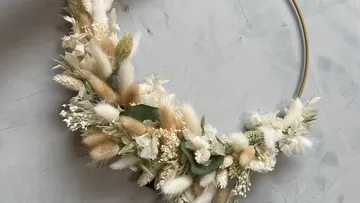 Flower wreath hangs, elegantly arranged, against a grey wall.