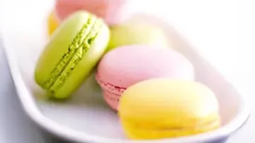 Colourful macaroons lie on a white plate.