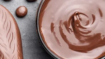 Chocolate cream in a bowl surrounded by drops of chocolate.