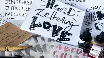 Handlettering-Übungen liegen auf einem Tisch, um kreativ zu sein.