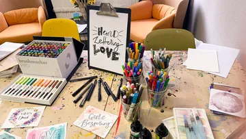 Colourful craft material on a table surrounded by chairs