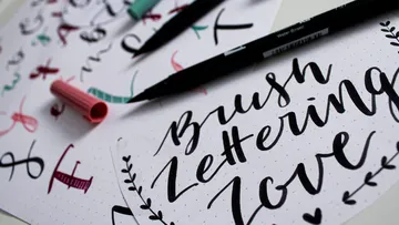 Colored pencils and papers show handwritten letters and words.
