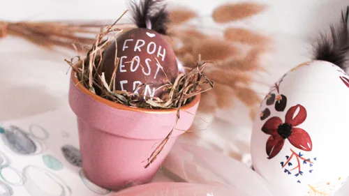 Colourful easter eggs in a flower pot with straw