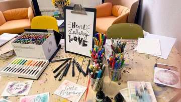 Colourfully marked pens lie on an artistic table.