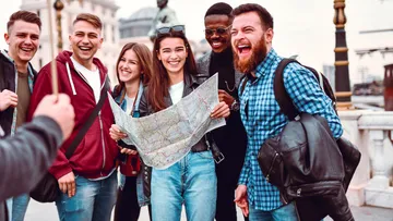 Group smiles as they look at a map outside.