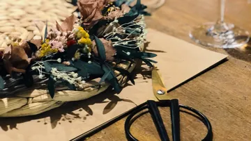 Ein geflochtenes Körbchen mit getrockneten Blumen auf Tisch.