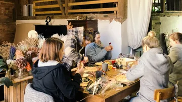 Women make crafts with dried flowers in a room.