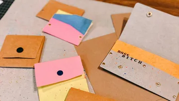 Colourful envelopes lie on a table, creatively arranged.