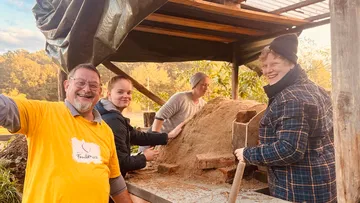 Gruppe arbeitet gemeinsam an einem Sandhaufen im Freien.