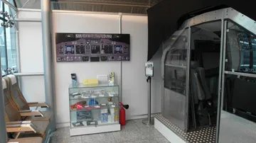 Flughafenbereich mit Flugzeugsimulator und Informationsstand.