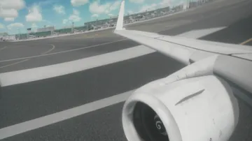 Flügel und Triebwerk eines Flugzeugs bewegen sich über die Landebahn.
