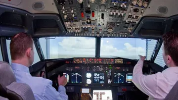 Zwei Piloten steuern ein Simulator-Cockpit mit Instrumenten.