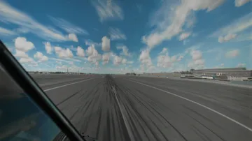 Piste im Vordergrund, Flugzeug rollt, sonniger Himmel.