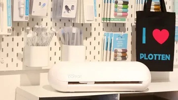 White cutter works on the wall in front of colorful creative materials.