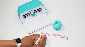 A cutter cuts colorful text onto paper.