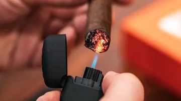 Zigarette wird mit Feuerzeug angezündet, handliche Umgebung.