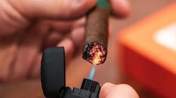 Cigarettes are lit with a lighter, warm light is visible.