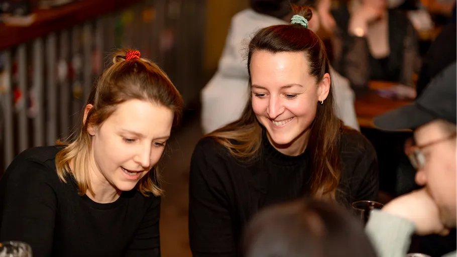 Zwei Frauen lachen und unterhalten sich in einem Restaurant.