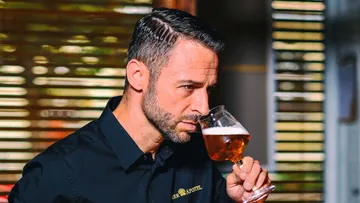 Mann schmeckt Bier aus einem Glas in modernem Ambiente.