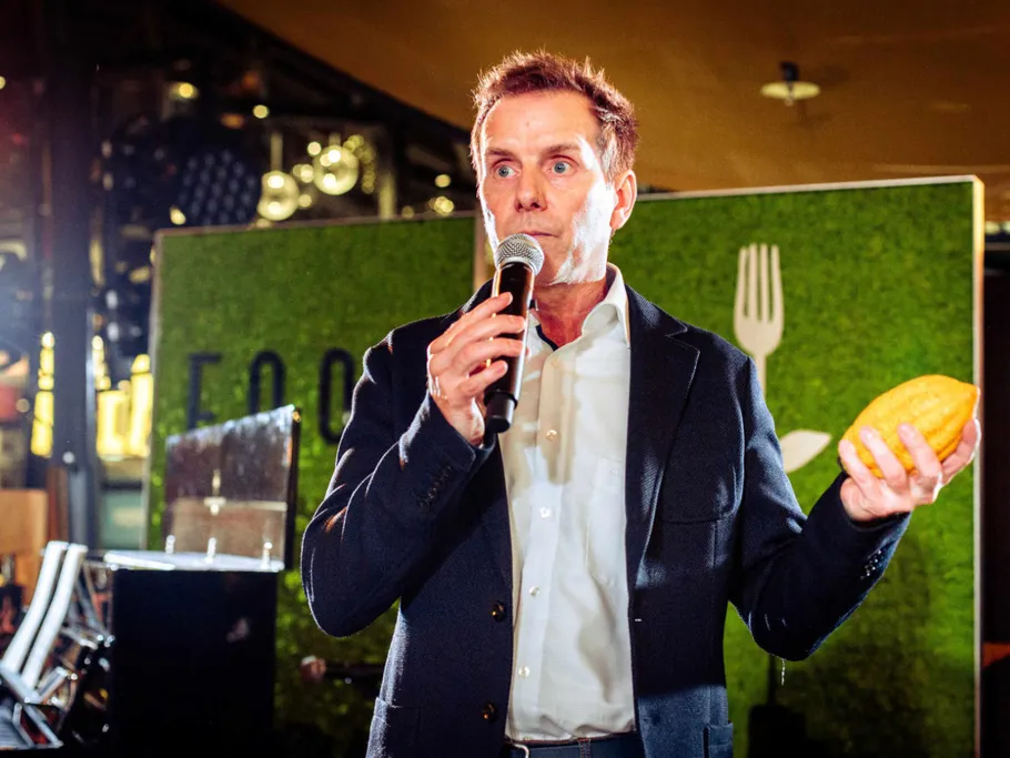 Man talking to a microphone and holding a yellow fruit.