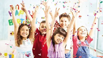 Fünf Kinder feiern mit Konfetti und Freude in einer Party.