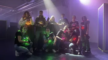 Gruppe spielt Lasertag in dunkler, beleuchteter Umgebung.