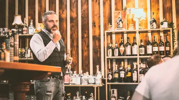 Man talking and holding a drink in a bar.