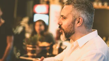 Man speaks thoughtfully in a lively environment.