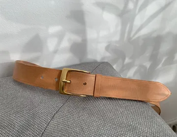 Brown leather belt on gray fabric surface.