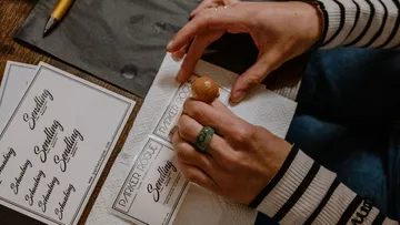 Hände stempeln Karten auf einem Tisch mit Papier.