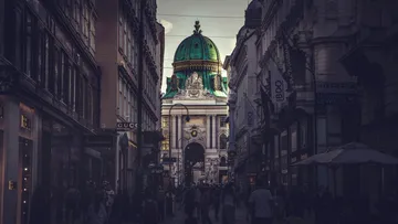 Elegante Gebäude mit grünem Dach in belebter Straße.