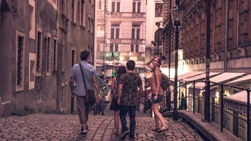 Fünf Personen gehen eine steinerne Straße in einer Stadt.