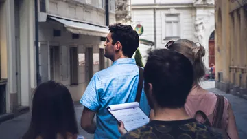Gruppen von Menschen gehen in einer engen, städtischen Gasse.