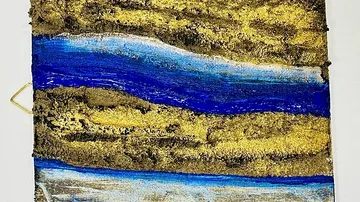 Abstract landscape with layers of gold and blue paint.
