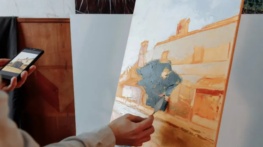 An artist paints on a canvas with a brush.