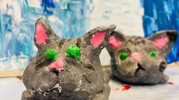 Two painted cat figures lie on a surface.