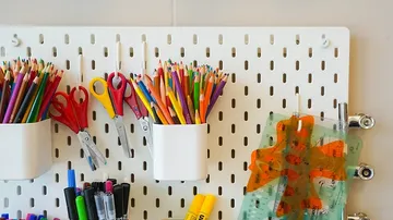 Colourful pens and scissors are attached to a wall bracket.