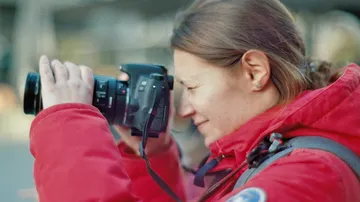 A woman takes pictures with a camera in an urban environment.