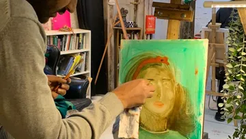 Person painting on canvas in studio.