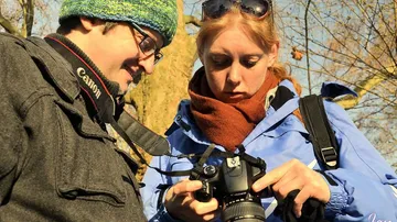 Two people are looking at a camera outdoors together.