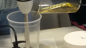 Blender pours a liquid into a transparent container.