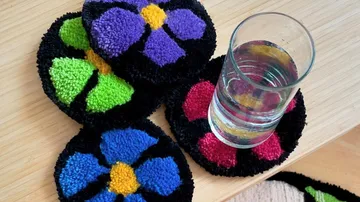 Bunte Untersetzer halten ein Glas Wasser auf einem Tisch.