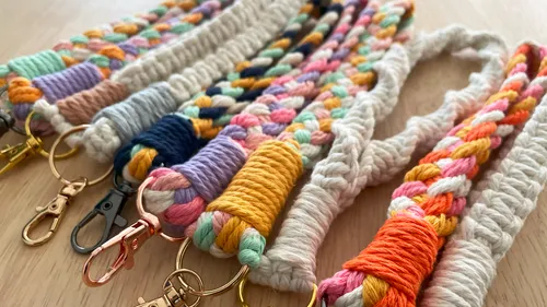 Bunte, geflochtene Gurte liegen auf einer Holzoberfläche.