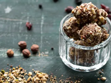 Glas mit Snacks, umgeben von Nüssen und Früchten.