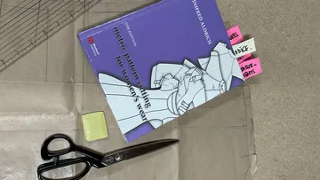 Buch, Schere und Radiergummi auf einem Tisch zum Schneiden.