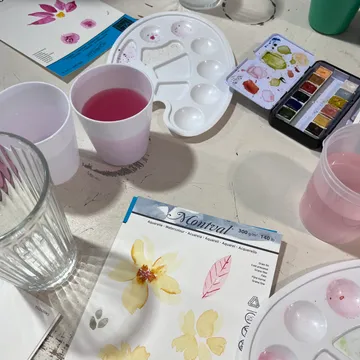 Watercolors, brush and paper on a table.