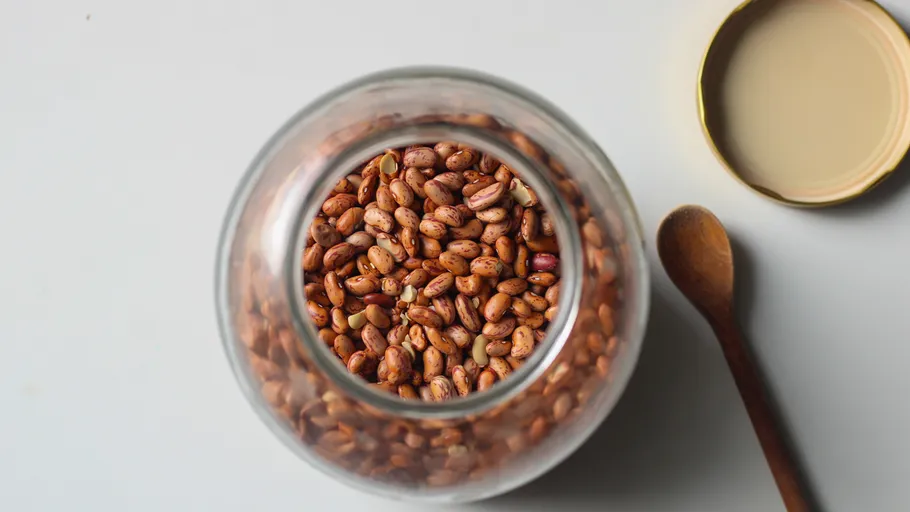 Jar of beans with wooden spoon.