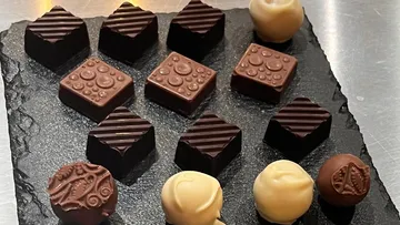 Chocolate chocolates lie on a black plate.