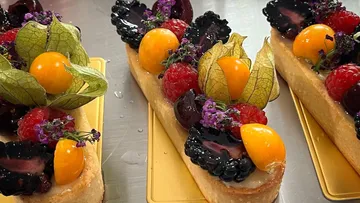 Bunte Torten mit frischen Früchten auf goldenen Platten.